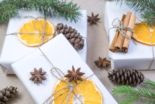 New Year's composition. On beige craft paper, gift boxes, dry orange slices, pine cones, cinnamon, cloves, spruce branches. Cozy Christmas concept