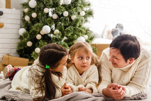 A happy mother hugs her two daughters at christmas