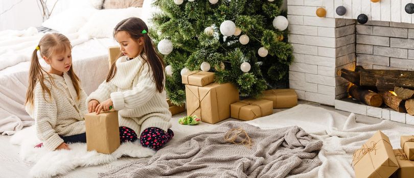 Kids little sisters hold gifts boxes interior background. What a great surprise. Small cute girls received holiday gifts. Best toys and christmas gifts. Children friends excited unpacking their gifts.