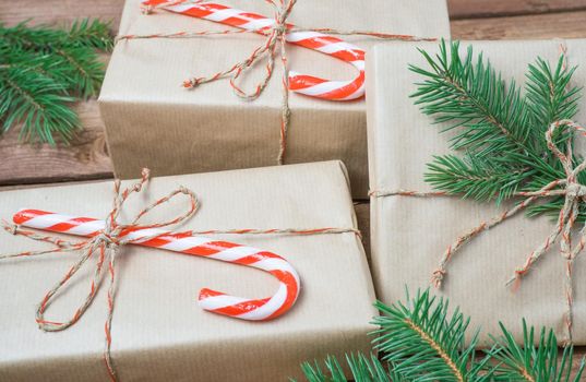 Christmas presents or gift box wrapped in kraft paper with decorations and fir branch on rustic wooden background