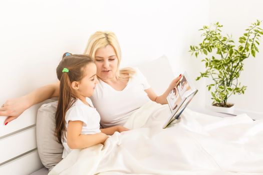 mother and daughter in bed watching a photo book