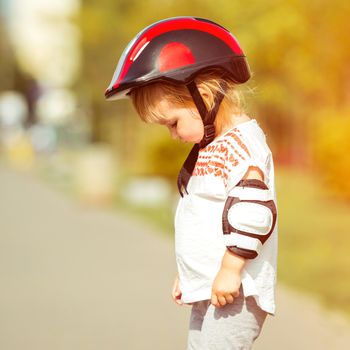 two year old pretty girl in a helmet on the street close-up