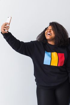Happy afro american woman taking selfie in studio on white background