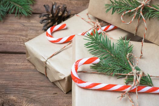 Christmas gifts or gift box wrapped in kraft paper with decorations, pine cones and fir branches on a rustic wooden background