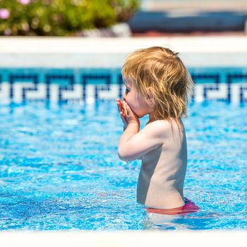 smiling cute little baby girl swims in the pool in summer