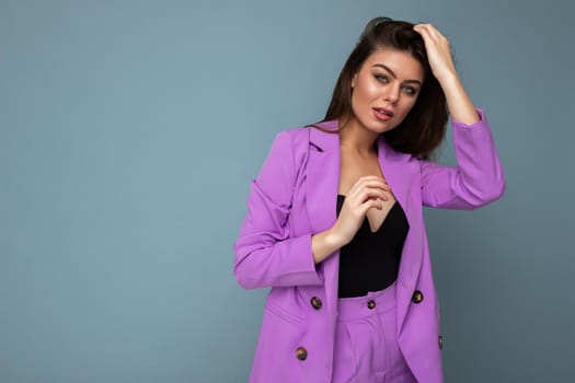 Photo of positive young business long hair brunette woman wearing purple suit isolated on blue background. Copy space.