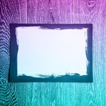 Black painted frame on white paper on wooden background with neon light - image