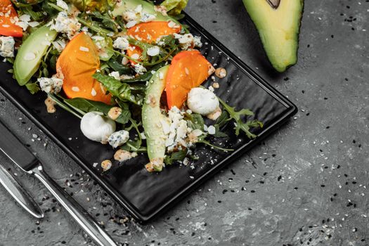 Fresh salad with fruits and greens on dark canvas background. Healthy food.