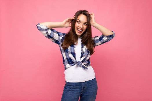 Young beautiful brunet woman. Trendy lady in casual summer hipster shirt . Positive female shows facial sincere emotions. Funny model isolated on pink background with free space.
