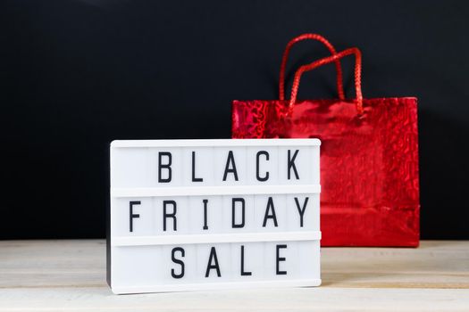 Black Friday sale. Red shopping bag and lightbox on dark background. Banner for advertising.