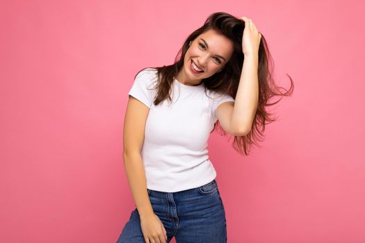 Portrait of positive cheerful fashionable woman in casual t-shirt for mock up isolated on pink background with copy space.