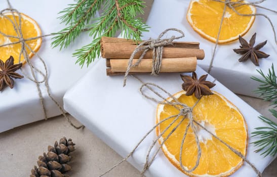 New Year's composition. On beige craft paper, gift boxes, dry orange slices, pine cones, cinnamon, cloves, spruce branches. Cozy Christmas concept