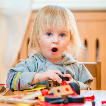 cute two-year old baby girl at home in the nursery playing with constructor
