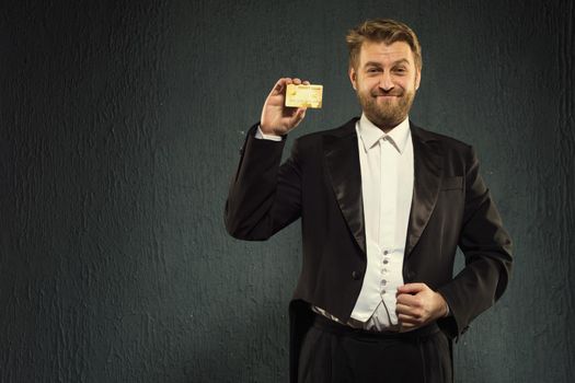 Positive man in a tailcoat offers a credit card. - image