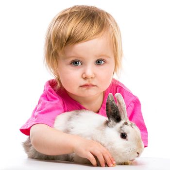 baby girl in a pink T-shirt with her small white rabbit on white background