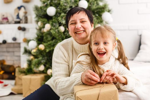 Mother and daughter unwrapping a present lying on the floor in the living room.