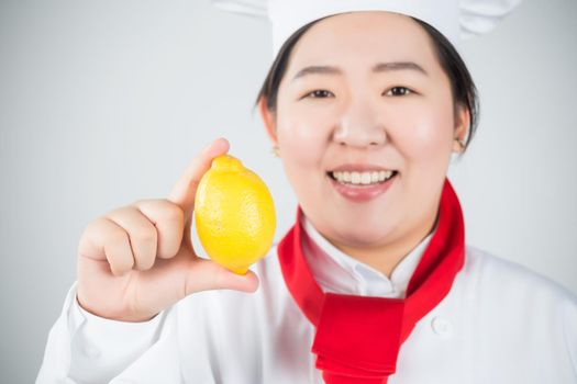 cooking and food concept - smiling female chef, holding a lemon