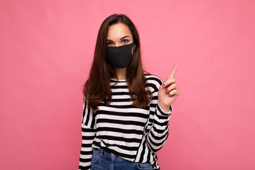 Photo of young attractive woman wearing handmade cotton fabric face mask isolated over colourful background wall. Protection against COVID-19. Copy space