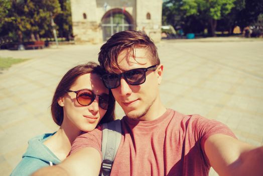 Smiling tourist young couple in love taking selfie portrait outdoor in summer at sunny day