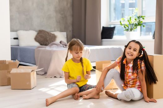 Excited funny kids girls running inside luxury big modern house on moving day, cute children entering exploring new home, happy young family buying real estate