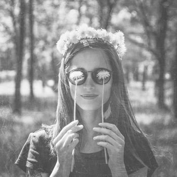 Smiling beautiful girl in wreath of dandelions closed her eyes with dandelions in summer park, concept of summer mood. Black and white image