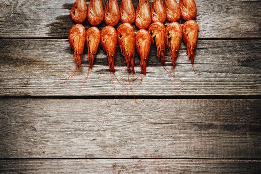 Red boiled shrimps on a wooden background, space for text