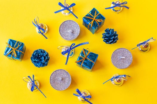 Christmas composition. Candles and Christmas decorations in blue on a yellow background. Flat lay, top view, copy space