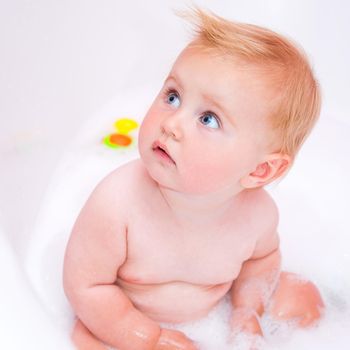 pretty baby girl is taking a bath with a foam