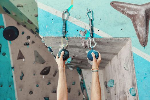 Man exercise in climbing gym, climber man gripping handhold, view of hands