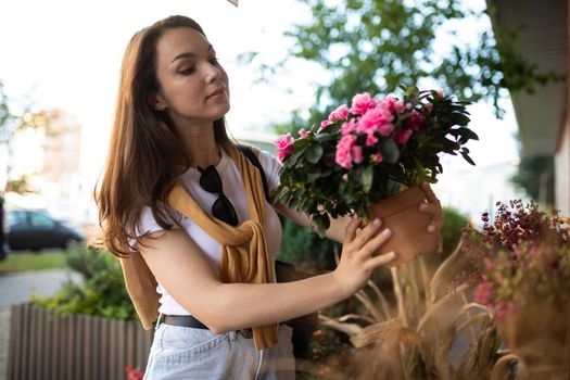 cute young woman holding her favorite flowers in a street garden shop.