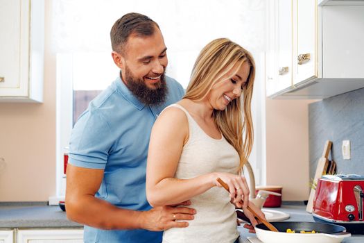 Young loving couple cooking together in kitchen at home