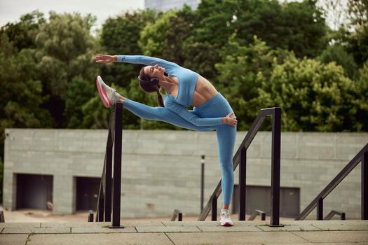 Beautiful fit caucasian woman is doing exercises outdoors at the city