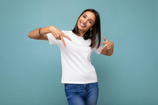 Photo of attractive positive smiling young woman pointing fingers down at copyspace presenting ads promo with wow omg sincere emotions wearing good look outfit isolated over background with free space.