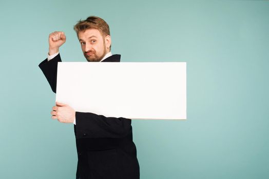 Funny young business man showing blank signboard, on blue background