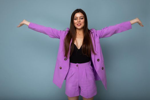 Portrait of happy joyful positive beautiful fashionable brunette woman in casual trendy violet jacket isolated on blue background with free space.