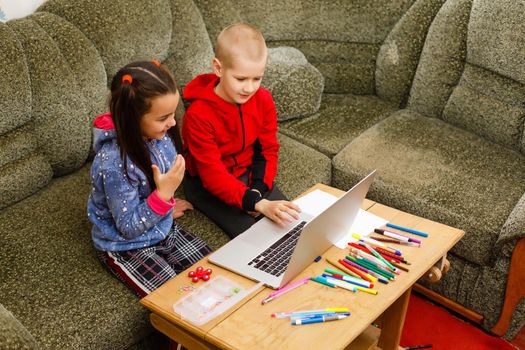 Distance learning online education. school boy and girl studying at home with laptop notebook and doing homework. Sitting at a table