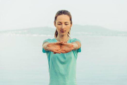 Sporty young woman stretching her hands outdoor, workout