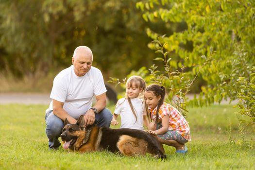 grandfather and two granddaughters are walking in the park