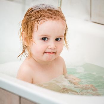 cute two year old baby bathes in a bath with foam closeup