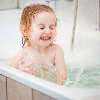 cute two year old baby bathes in a bath with foam closeup