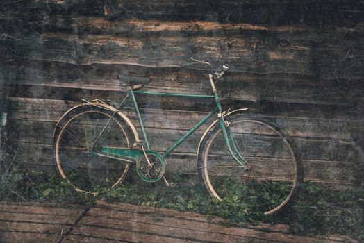 Old-fashioned bicycle on background of wooden house outdoor. Image with retro textured effect