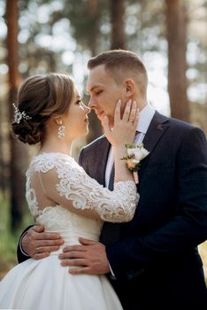 the bride and groom are walking in a pine forest on a bright day