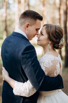 the bride and groom are walking in a pine forest on a bright day