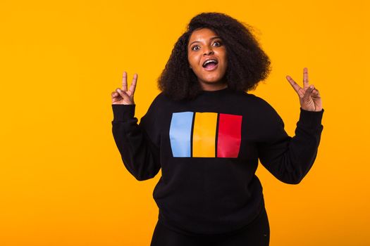 Youth fashion concept - Confident sexy black woman in stylish hoodie having fun on yellow background