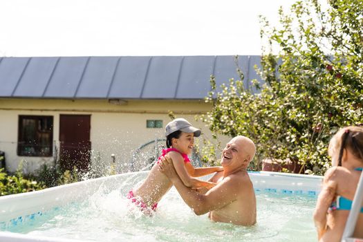 Portrait of a happy grandfather with grandchildren in pool