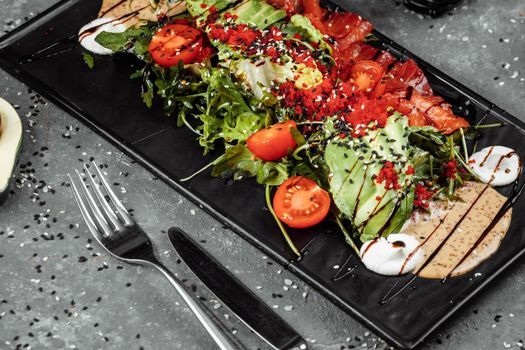 Salmon salad gravlax. Smoked salmon salad, with mixed greens cherry tomatoes avocado black olives carrots sprouts cucumber and lime. Delicious healthy eating.