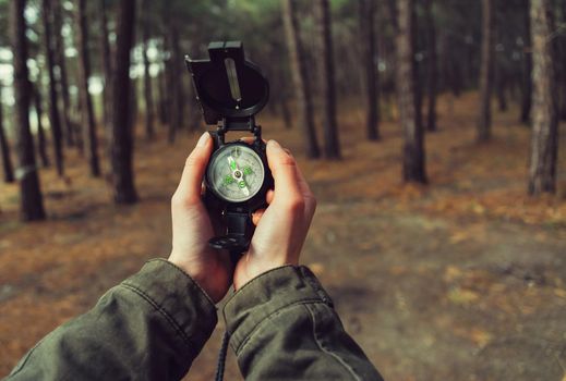 Hiker woman holding a compass in the forest. View of hands. Point of view shot