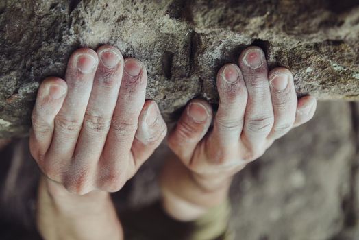 Close-up of male climber hands in magnesium powder on stone rock