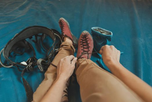 Sporty woman putting on climbing shoes and preparing to climb, point of view shot