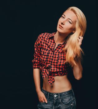 Fashionable beautiful blonde young woman wearing in plaid shirt and jeans, woman looking at camera